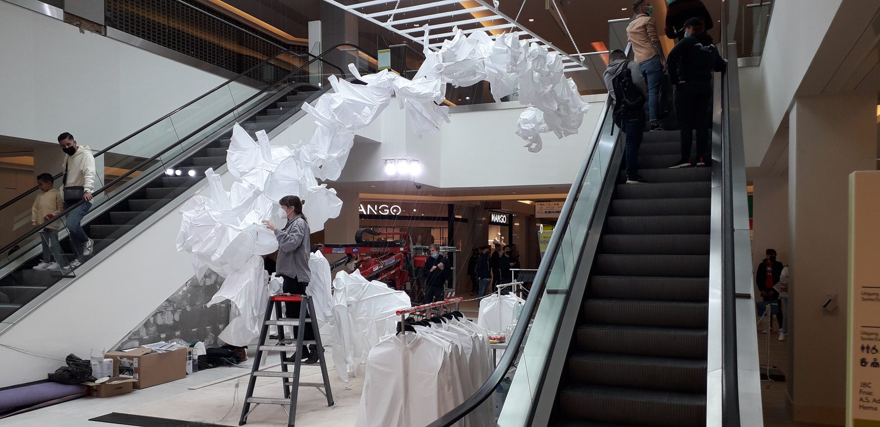 The textile installation being rigged above the escalators