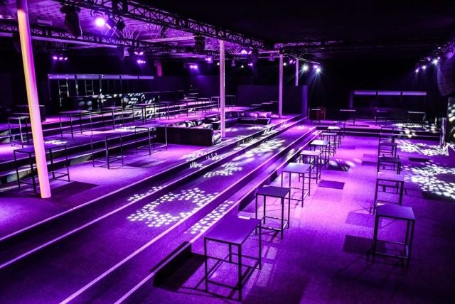 The empty room with seating tiers and standing tables, ready to open